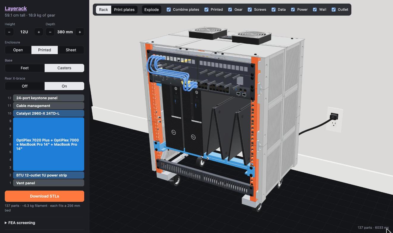 A 12U printed rack with a Cisco switch, two Dell OptiPlex SFFs and two tented MacBooks, cables routed